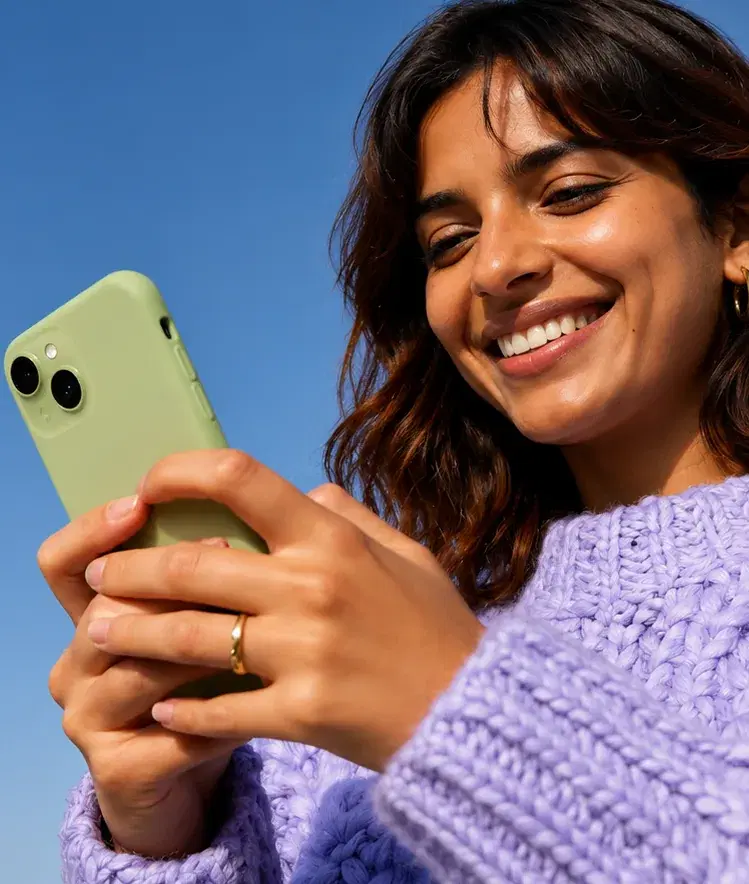 A smiling woman checking charger availability on her phone under a clear blue sky